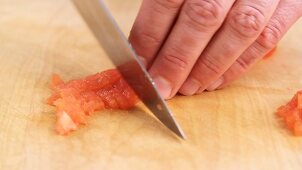 A peeled tomato being diced