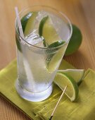 Ein Glas Gin Tonic mit Limetten auf grüner Serviette