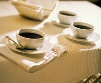 Schwarzer Kaffee in drei weissen Tassen auf einem Tisch