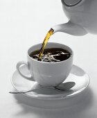 Schwarzer Kaffee wird aus Kaffeekanne in eine Tasse gegossen