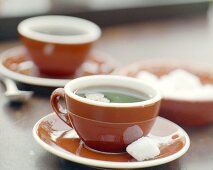 Kaffee in braunen Tassen mit Zuckerwürfeln