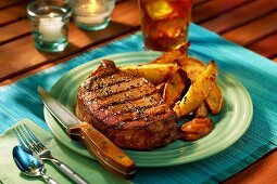 Barbecued ribeye steak with baked potato wedges