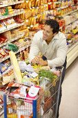 Smiling man with full shopping trolley in a supermarket