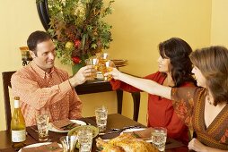 Man and Women Toasting with White Wine at Thanksgiving Table