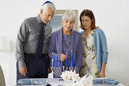 Woman with Man and Woman Lighting the Manora for Hanukkah