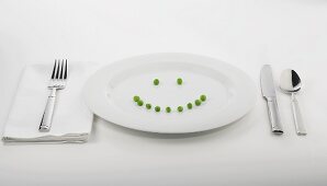 Place Setting with Peas Forming a Smiley Face on White Plate