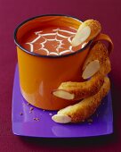 Kürbissuppe in einer Tasse mit Fingern aus Brot zu Halloween