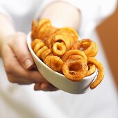 Hände halten Geschirr mit Pommes-Frites-Spiralen