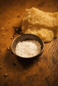 Coarse Salt in a Small Bowl on Wooden Table with Peppercorns and Parmesan Cheese