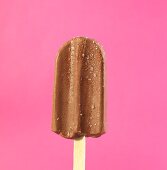 A chocolate ice lolly against a pink background