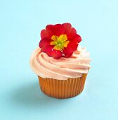 Cupcake with Orange Frosting and Red Primrose Garnish