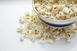 Bowl of Popcorn; Popcorn Spilled Around Bowl; White Background