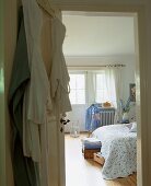 Blick vom Badezimmer in ein helles Schlafzimmer mit stummem Diener und großem Doppelbett