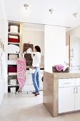 A woman puting laundry away in a large, light utility room