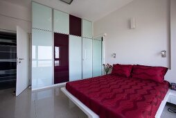 Grosszügiger Schlafraum mit Glaswand & rotbezogenem Doppelbett