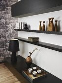 A stylish corner of a living room - black shelving on the floor and the wall