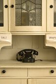 White crockery cupboard with old fashioned telephone