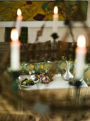 View through hanging candlesticks onto a metal table with flower vases