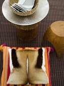 Pillows with hide covers and rustic stool with a shiny white dish