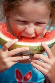 A little girl eating a slice of watermelon
