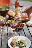 A table laden with antipasti and rosé wine in a garden
