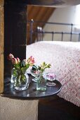 Roses and carnations in a glass vase on a shelf in a bedroom