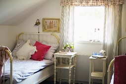 Ländliches Dachzimmer mit Einzelbett und weißem Nachttisch