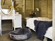 A rustic room with wooden walls - a fur on a bed and a white make-up table