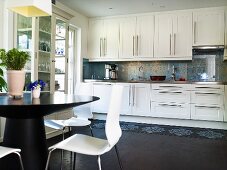 An open-plan kitchen - a view of a white fitted kitchen with stainless steel handles