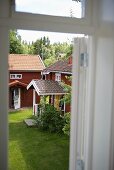 A view through a window of a wooden house with a porch