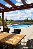 A covered terrace with a view of a pool