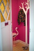 Open front door with a view of a white coat rack and pink foyer walls