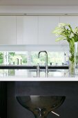 A kitchen counter - a sink with designer taps and a white shiny work surface