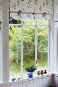 A window with a floral blind and a view onto a garden