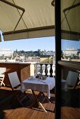 View of a roof terrace with set table under an awning and a view of a city