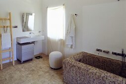 Ländliches Bad - Badewanne mit braunen Mosaikfliesen und Waschtisch mit Spiegel am Fenster