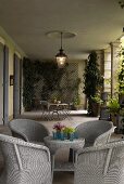 Hellgraue Korbmöbel und Pflanzenkübel in Loggia einer Villa mit Laterne an der Decke