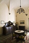 Vaulted ceiling with a wrought iron chandelier above a table and antique chairs