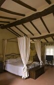 Bedroom under the roof - elegant canopy bed under a rustic beam ceiling