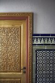 Carved wooden door and white and blue oriental wall tiles