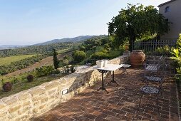 Terrace with a table and chairs on terracotta flooring with a view of the Mediterranean countryside