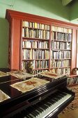 Living room with piano and mahogany bookcase against green wall