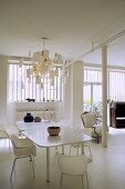 Dining room in a white loft -- white table with chairs and ceiling lamp with sheets of memo pad paper