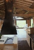 Open fireplace with a black flue under the wooden beam ceiling of a renovated country home