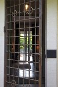 Rusty door grill and a view into an illuminated entrance