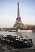 Sunny day in Paris - house boat docked on the bank with a view of the Eiffel tower