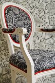 Gepolsterter Stuhl mit schwarz weißem Bezug vor weiss schwarzer Tapete an Wand