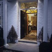 Evening atmosphere - Christmas decoration in the entrance of a country house with pillars and a view into a illuminated living room