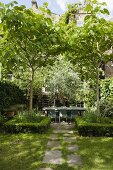 Sonniger Tag im Garten mit Hecke um Baum und idyllischer Terrassenplatz