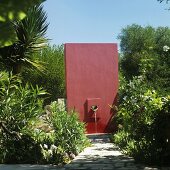 A dark red wall with a water spout in a Mediterranean garden
